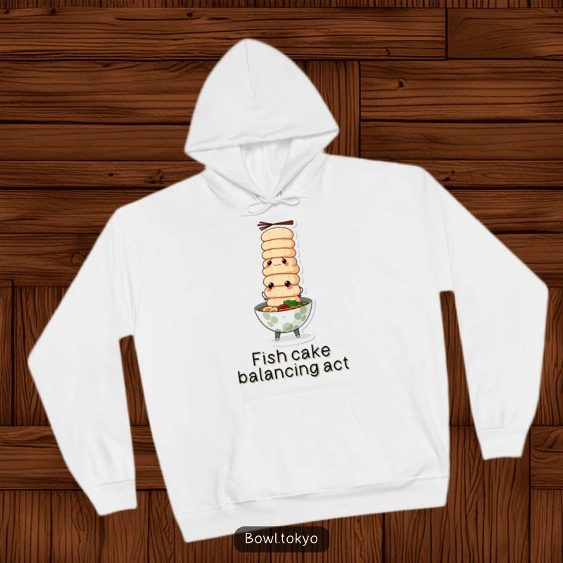 Funny ramen bowl hoodie, intensely focused, flawlessly balancing a precarious tower of fish cakes, a testament to skill.