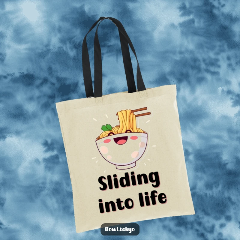 Funny tote bag with a happy ramen bowl character grinning while sliding down a noodle, great for carrying joy.